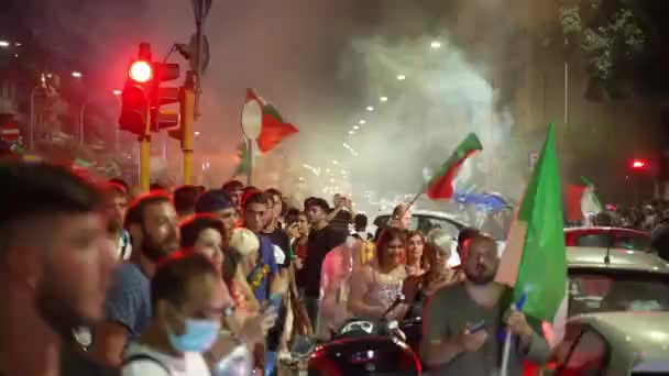 ROMA, ITÁLIA - JULHO 11, 2021: Multidão de hooligans italianos nas ruas de Roma após a vitória no torneio final de futebol UEFA EURO 2020, caras bloqueando estradas, queimando foguetes de fumaça vermelha, levando — Vídeo de Stock