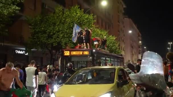 РИМ, ИТАЛИЯ - 11 июля 2021 года: Пьяные забавные итальянские хулиганы с флагами, танцующие на крыше автобуса, прыгающие и кричащие, толпа людей, блокирующих проезд транспорта по улицам Рима. Футбольные фанаты — стоковое видео