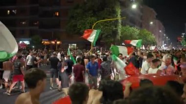 ROME, ITALY - 11 Temmuz 2021: UEFA EURO 2020 'deki futbol takımının zaferinden sonra yolları kapatan bayraklı İtalyan taraftarlar yolda dans ediyor, sevinçle zıplıyor ve bağırıyorlar