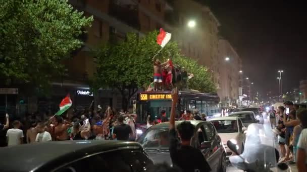 ROMA, ITÁLIA - JULHO 11, 2021: Bêbado rua engraçado hooligans italianos dançando no telhado do ônibus, pulando, gritando e acenando bandeiras, multidão de pessoas bloqueando o transporte de passagem nas ruas de Roma. Futebol — Vídeo de Stock