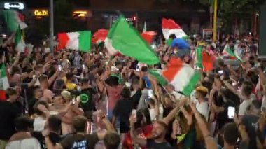 ROME, ITALY - 11 Temmuz 2021: UEFA EURO 2020 'deki futbol takımının zaferinden sonra yolları kapatan bayraklar sallayan mutlu İtalyan taraftarlar ve taraftarlar, yolda dans eden sokak taraftarları