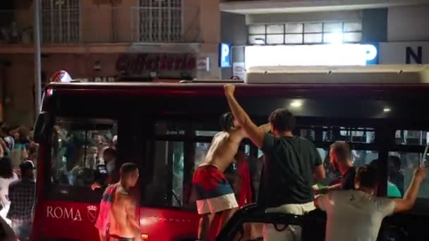 ΡΩΜΗ, ΙΤΑΛΙΑ - 11 ΙΟΥΛΙΟΥ 2021: Μεθυσμένος χούλιγκαν δρόμου χωρίς T-shirt αναρρίχηση στην κορυφή της οροφής των λεωφορείων μπλοκαρισμένο από το πλήθος των οπαδών στο δρόμο της Ρώμης μετά τη νίκη της αθλητικής ομάδας στην UEFA EURO 2020. Εξοργισμένος — Αρχείο Βίντεο