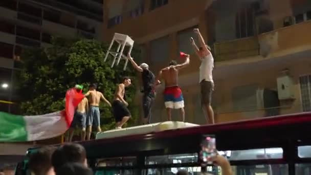 ROME, ITALY - 11 Temmuz 2021: UEFA EURO 2020 'deki futbol takımının zaferini kutlayan öfkeli İtalyan taraftarları, ellerinde bayraklar ve plastikle otobüsün çatısına tırmanan sarhoş adamlar — Stok video