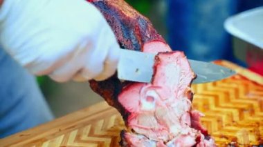 Ahşap kesim tahtasında çıtır çıtır kuzu budu, baharatlı kuzu budu ve geleneksel barbekü festivali için hazırlanmış baharatlı kuzu budu dilimleme işlemi. Eski kuzu bacağı tarifi.