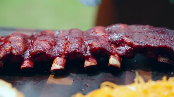 Chef cualificado en guantes de goma arrojando huesos de costillas de cerdo asadas con corteza crujiente, hombre preparando jugosas costillas de cerdo para la fiesta de barbacoa. Deliciosas costillas humeantes en cámara lenta, barbacoa concepto de parrilla — Vídeos de Stock