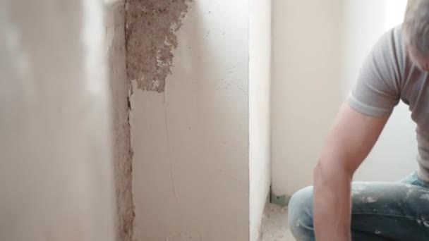 Reparação de obras no canteiro de obras, gesso alinhando parede sob a janela com pasta spackling branqueamento e espátula de metal. Processo de gesso paredes em novo apartamento, revisão conceito — Vídeo de Stock