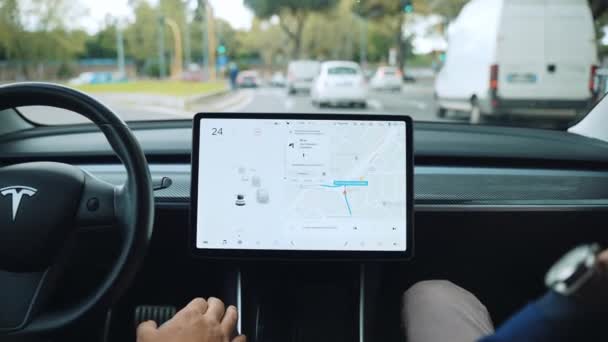 ROME, ITALY - APRIL 28, 2021: Back view of electric Tesla car interior with touchscreen monitor display, driver showing autopilot function and then holding steering wheel driving with friend — Stock Video