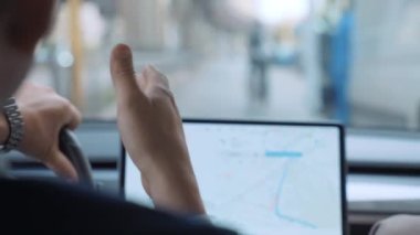 Başarılı bir işadamı yüksek teknolojili Tesla arabasıyla şehir merkezinde araba sürüyor. Yanında erkek arkadaşı, direksiyon başında, arkadaşlarıyla konuşuyor, arka planda el kol hareketi yapıyor.