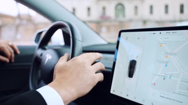 РИМ, Италия - 28 апреля 2021 года: Человек в деловом костюме проводит тест-драйв высокотехнологичного электромобиля Tesla Model 3 автономного автомобиля, водитель включает и выключает функции на рулевом колесе, соединенном с — стоковое видео