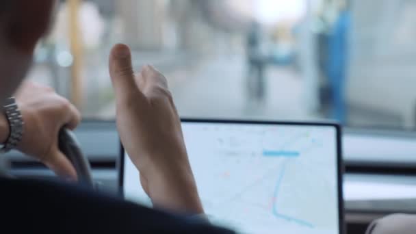 Exitoso hombre de negocios que conduce a lo largo de la calle del centro de la ciudad en alta tecnología eléctrica Tesla coche Modelo 3 con colega masculino cerca, hombre volante, hablando con un amigo, gesto con la mano sobre el fondo — Vídeo de stock