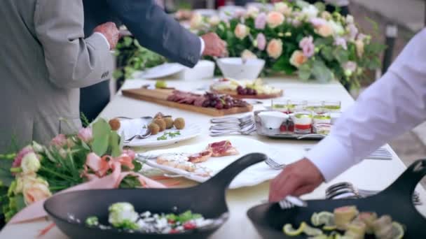 Mesa de banquete de casamento lindamente decorada com flores frescas e variedade de aperitivos e lanches servidos antes da refeição principal na recepção formal, buffet de mesa com pratos de catering e tábuas de madeira — Vídeo de Stock