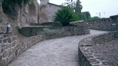 Ancient Italian residence villa with interior restaurant and courtyard, camera moving along the rising path road leading to the castle entrance. Historic landmark in the heart of Italy