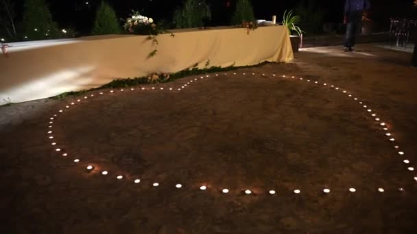 Brennende Kerzen in Herzform auf dem Boden, romantische Lichtdekoration für den Hochzeitstanz eines frisch vermählten Paares. Kerzenlicht als Symbol der Romantik und Leidenschaft zwischen Menschen in — Stockvideo