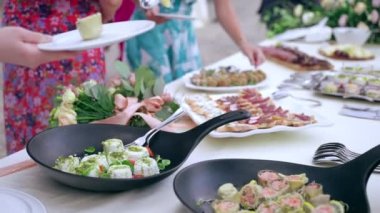 Luxury banquet menu table on wedding party, waiter serving wedding guests at buffet table putting variety of snacks, canapes and appetizers. Catering service on wedding party