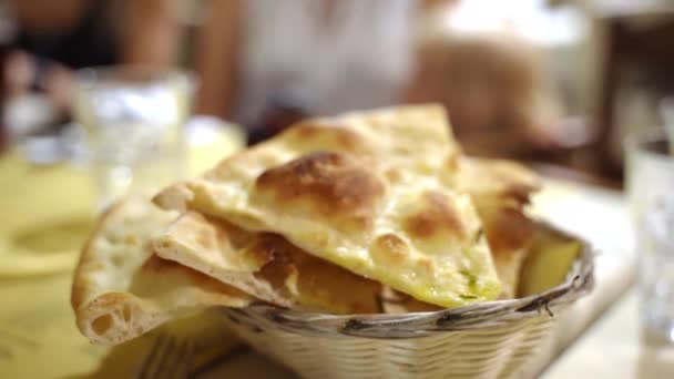 Geleneksel İtalyan restoranında bakire zeytinyağı, tuz ve biberiyeyle pişirilmiş altın çıtır Focaccia ekmeği kadın eli ağır çekimde Focaccia 'dan bir parça alıyor. Geleneksel İtalyan — Stok video