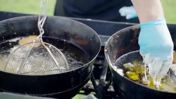 Servicio de catering bellamente organizado al aire libre en la recepción del restaurante o del hotel, camarero en guantes freír verduras y frutas con masa líquida en aceite de oliva chisporroteante utilizando calderos inoxidables — Vídeos de Stock