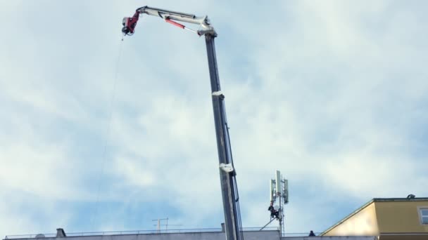 Dünyadaki telekomünikasyon gelişimi, İtalya 'daki inşaat sahasında çalışan ekip operatörleri konut binasının çatısına 5G kule anteni yerleştirmek için çalışıyorlar. Gökyüzünde inşaat vinci — Stok video