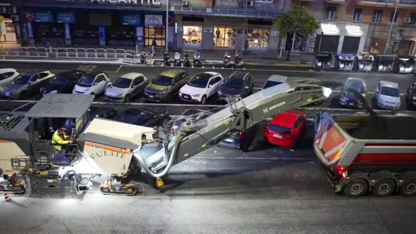 ROME, ITALIË - APRIL 9, 2021: Zware grader vrachtwagens rijden langs de straat met parkeerplaatsen in de woonwijk van Rome, verwijderen met druk oude geruïneerd asfalt en gooien in de passerende vrachtwagen — Stockvideo