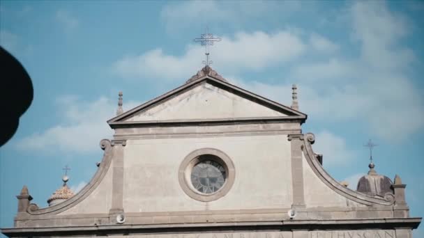 Italian ancient characteristic church facade in old Etruscan village, historical flagstone castle building exterior with round stained glass clock in the centre and latin inscription. Old church with — Stock Video