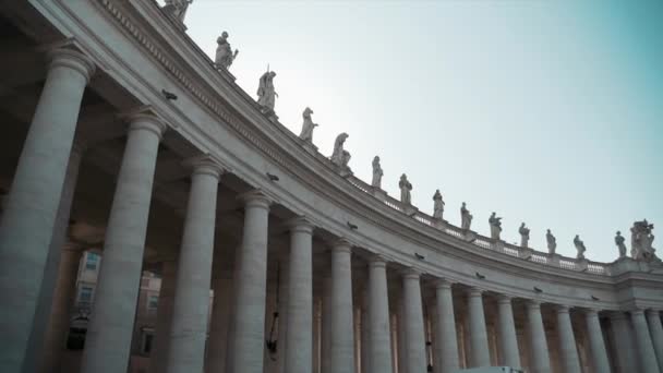 Majestueuze marmeren zuilen op het plein van St. Peters Basiliek kerk, marmeren beelden van apostelen op het dak op zuilen in zonlicht. Beroemde St. Peters Basiliek met zijn karakteristieke kenmerken — Stockvideo