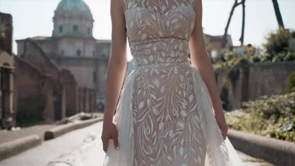 레이스 웨딩 드레스를 입은 아름다운 기혼 여성 이 유명 한 로마 포럼 건축 양식을 배경으로 천천히 걷고 있다. — 비디오
