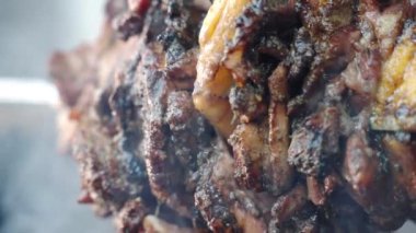 Sulu ve baharatlı domuz filetosu yavaşça bbq ızgarasında kızartılıyor kızgın ateşin ve kömür dumanının üstünde sallanıyor ızgaradan yağ damlıyor. Et çeşitleri bbq partisi ve piknik için kızartılıyor.