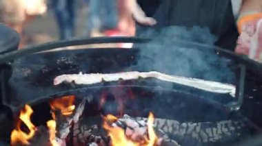 Eldivenli usta aşçı bbq piknik partisinde ızgara yaptığı için domuz pastırması dilimliyor, domuz pastırması kızartılıyor. Geleneksel arkadaşlar hafta sonu bbq partisi, millet.