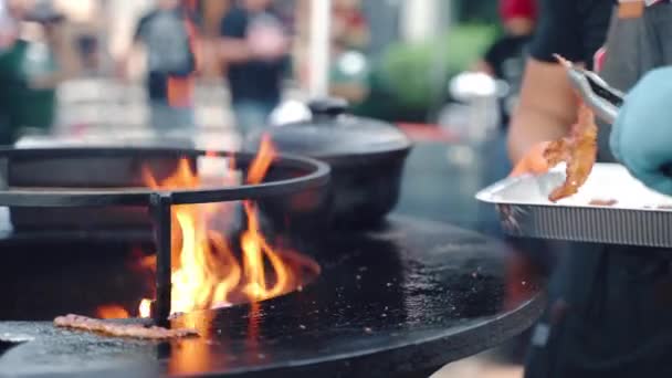 Amis se réunissant pour la fête de pique-nique week-end avec une large gamme de plats de viande et de collations, deux hommes en gants griller tranches de bacon sur barbecue fumeur et les mettre dans un récipient en aluminium pour — Video