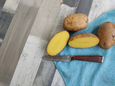 Patatesleri diğer patates yumrusu ve bir bıçakla birlikte mavi bir peçeteye yerleştirilmiş iki parçaya ayır. Fotoğrafı. Yukarıdan görüntüle.