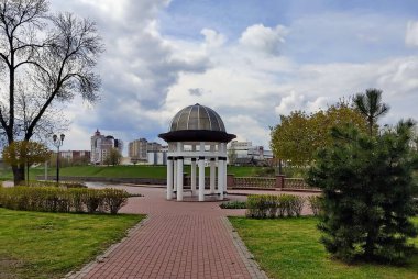 Şehirde beyaz kolonları olan yuvarlak balkon, nehir kıyısındaki toprak setinin üzerinde. Kümülüs bulutlu güzel bir hava fotoğrafı..