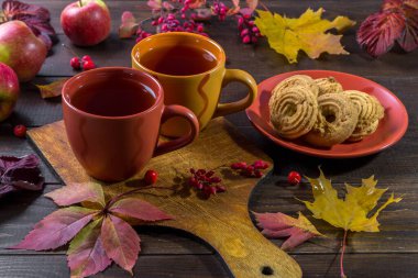 Kurabiyeli sonbahar çayı ve ahşap bir masada sonbahar yaprakları..