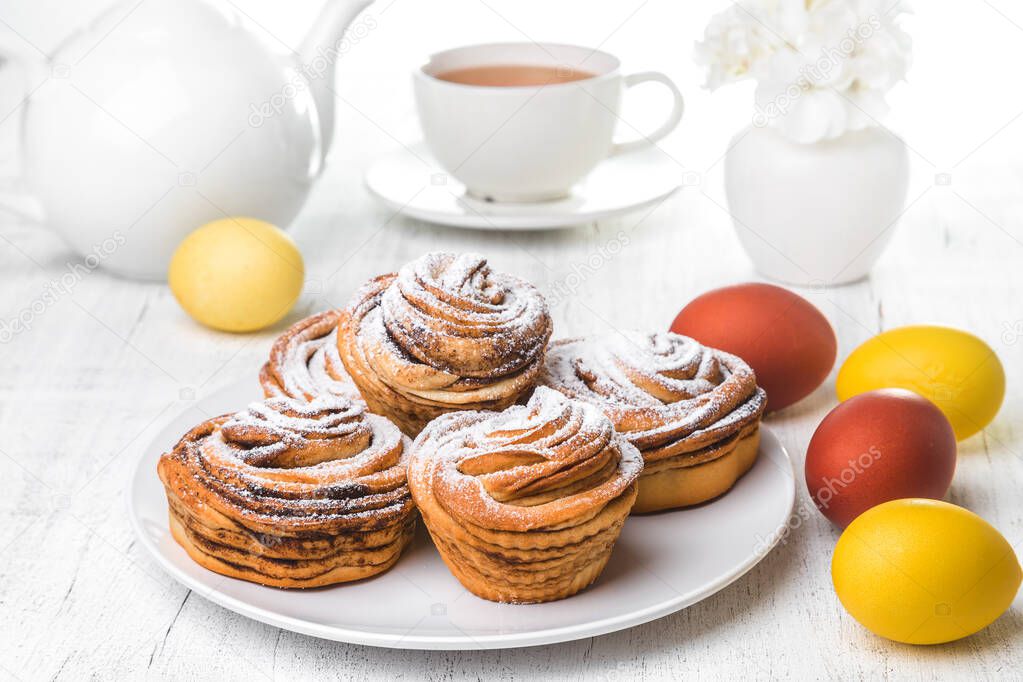 Easter background. Easter cake - Cruffin, Kraffin or Kulich with icing sugar on top on a white plate on a light background.