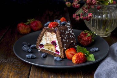 Çilek ve hanımeli bir porsiyon çikolatalı pasta, hanımeli ve muz, üzerine çilek ve hanımeli serpiştirilmiş..