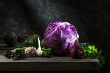 Kırmızı lahana ve sebzeler, koyu bir arka planda, ahşap bir masada..