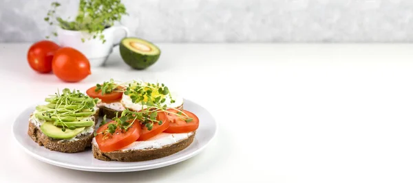 Whole wheat toast with curd cheese, tomatoes, avocado and microgreens.