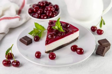 Beyaz bir masada bir tabak kirazlı cheesecake..