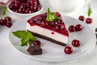 Beyaz bir masada bir tabak kirazlı cheesecake..