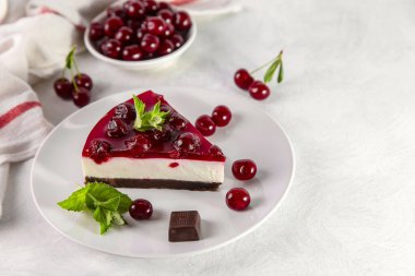 Beyaz bir masada bir tabak kirazlı cheesecake..