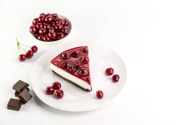 Beyaz bir masada bir tabak kirazlı cheesecake..