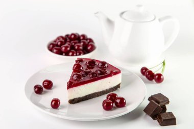 Beyaz bir masada bir tabak kirazlı cheesecake..