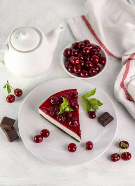 Beyaz bir masada bir tabak kirazlı cheesecake..