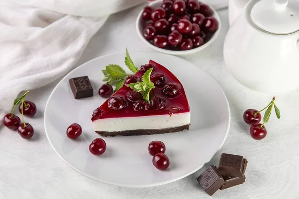 Beyaz bir masada bir tabak kirazlı cheesecake..