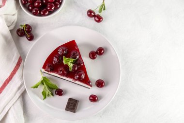 Beyaz bir masada bir tabak kirazlı cheesecake..