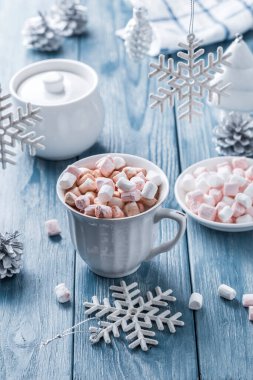 Mavi ahşap arka planda lokum ve Noel süslemeleri olan bir fincan lezzetli sıcak kakao..