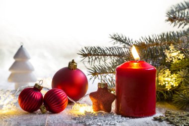 Kırsal ahşap tahtalardaki kırmızı Noel mumu - doğal elementler, dallar, çam kozalakları, Noel süslemeleri.