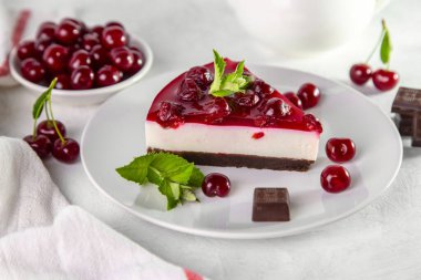 Beyaz bir masada bir tabak kirazlı cheesecake..