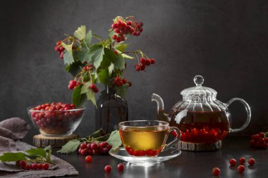 Şeffaf bir fincanda dikenli sıcak çay ve koyu arkaplanda çay..