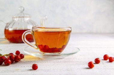 Şeffaf bir fincanda dikenli sıcak çay ve arka planda çay olan çaydanlık..