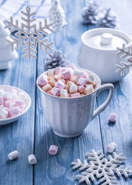 Mavi ahşap arka planda lokum ve Noel süslemeleri olan bir fincan lezzetli sıcak kakao..