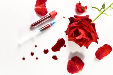 Kırmızı gül, kan damlaları, şırınga ve beyaz arka planda kan olan test tüpü..